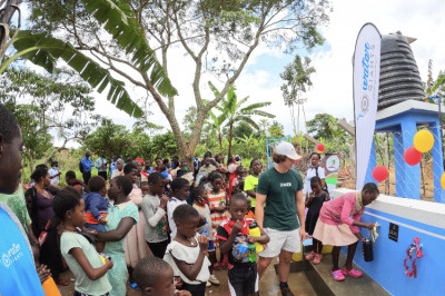 Adults providing a large group of people fresh water from a water station