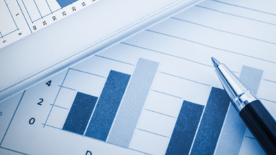 Ballpoint pen resting on paper sheets depicting bar graphs